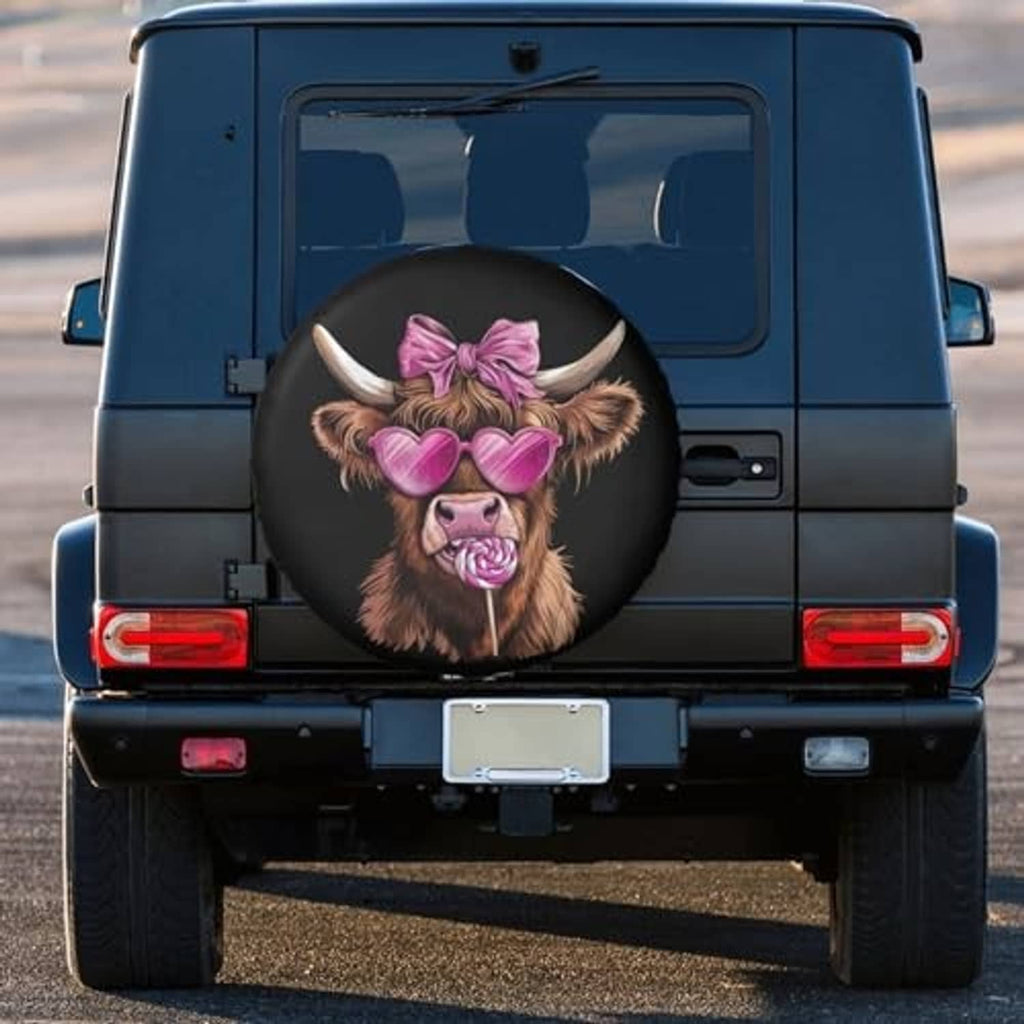 Round black spare tire cover with Highland cow face in pink heart glasses and bow on vehicle