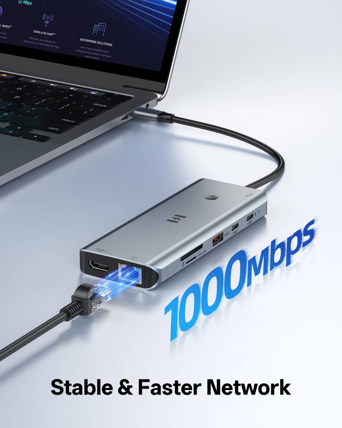 Space gray USB-C docking station with Ethernet and USB ports connected to a laptop