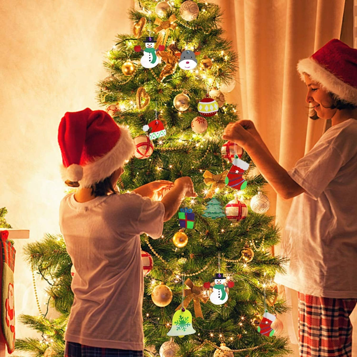 Painted wooden Christmas ornaments on a lit tree, including snowman and tree shapes