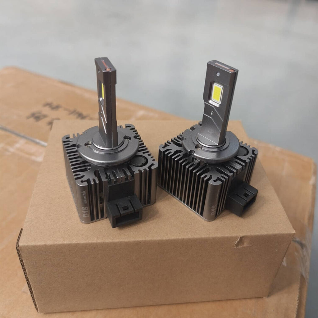 LED headlight bulb set on cardboard box with black heatsinks and yellow LED chips