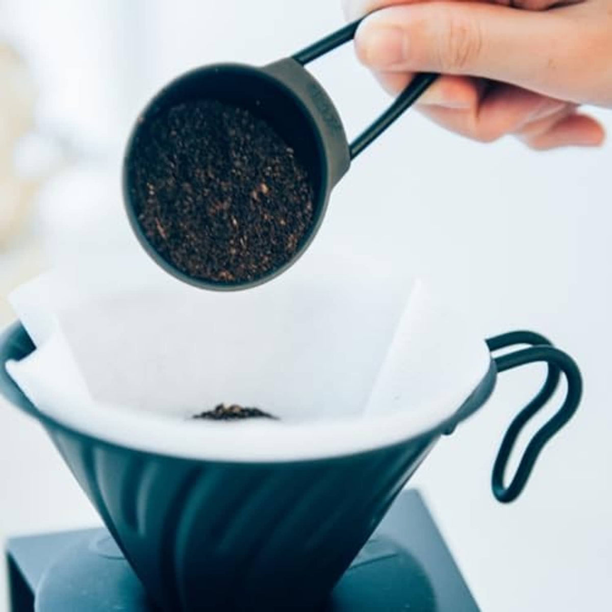 Paper coffee filter holding brewed coffee grounds in dripper