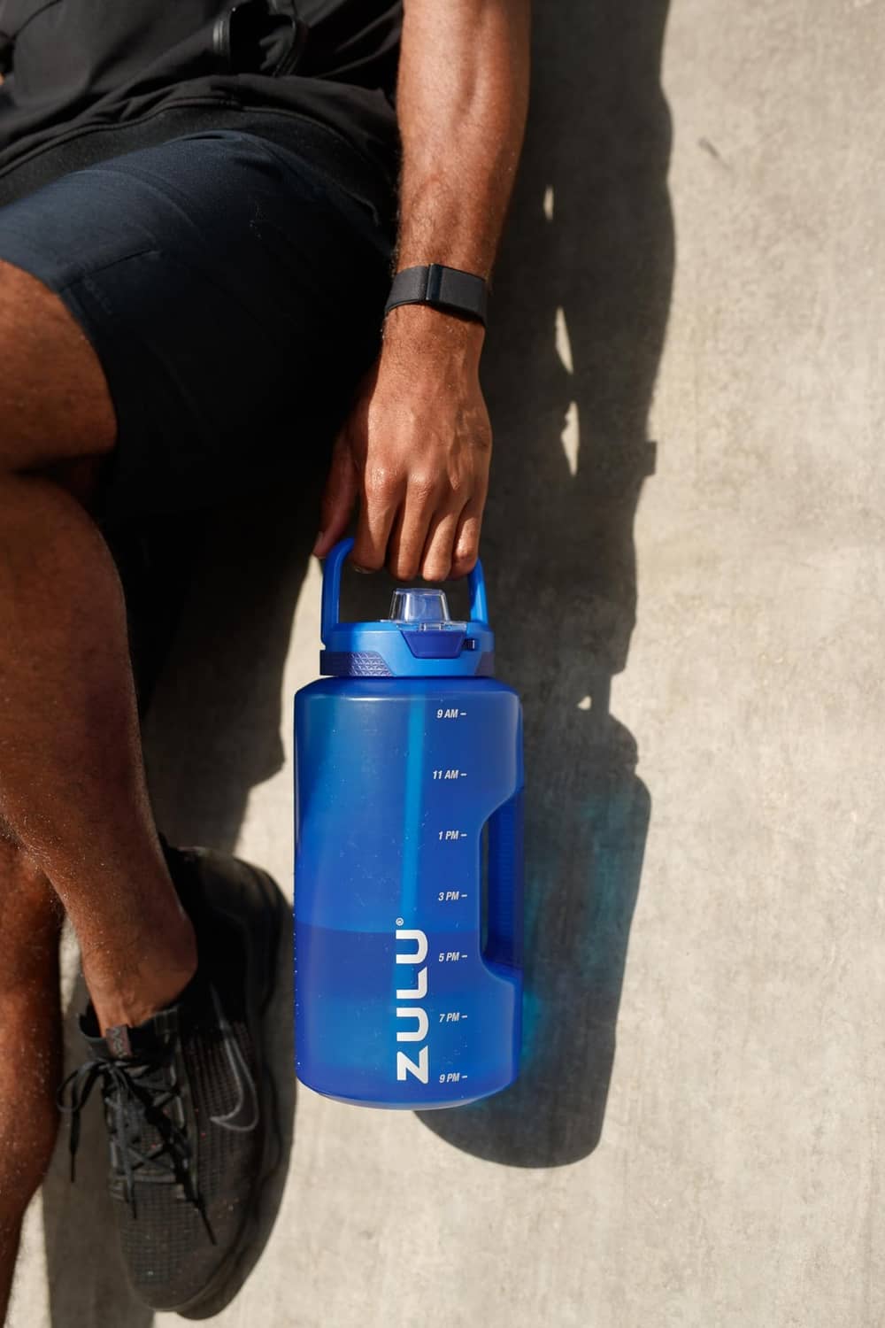 Royal blue water bottle held in hand, flip-top lid and carry handle opening