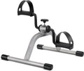Mini exercise pedal bike with silver frame, black handles, and adjustable seat for arms/legs