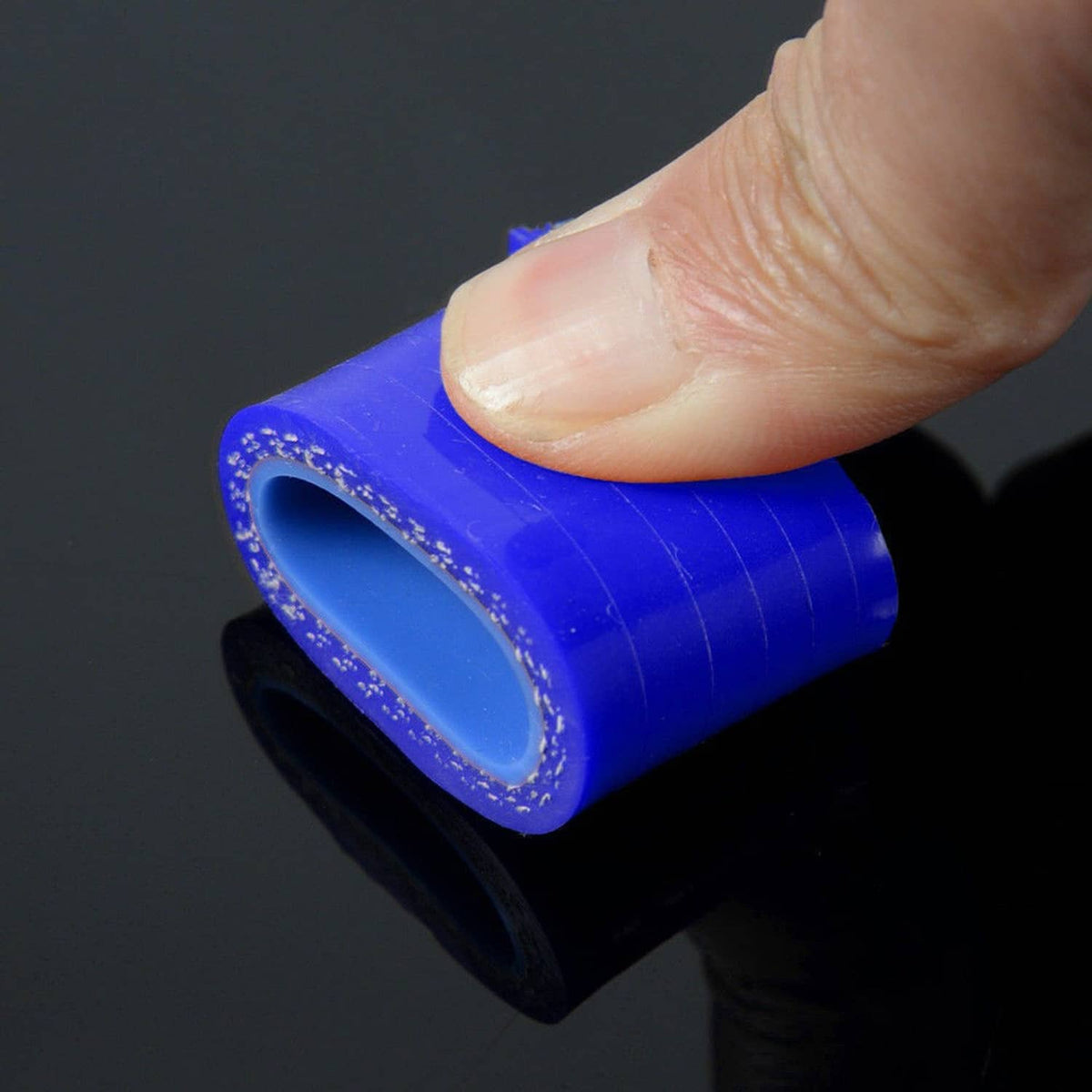 Small blue silicone radiator hose end with circular opening, held by fingers