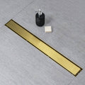 Gold linear shower drain grate with mounting stem, black threaded adapter, and leveling foot