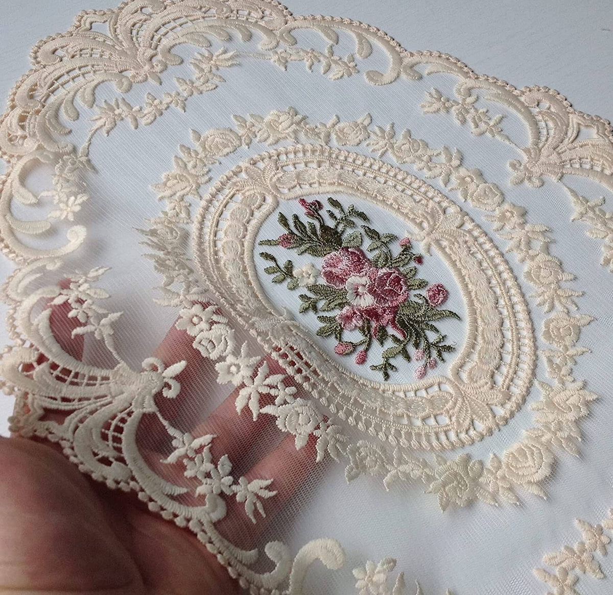 Light beige lace placemat close-up with embroidered oval floral center and raised trim