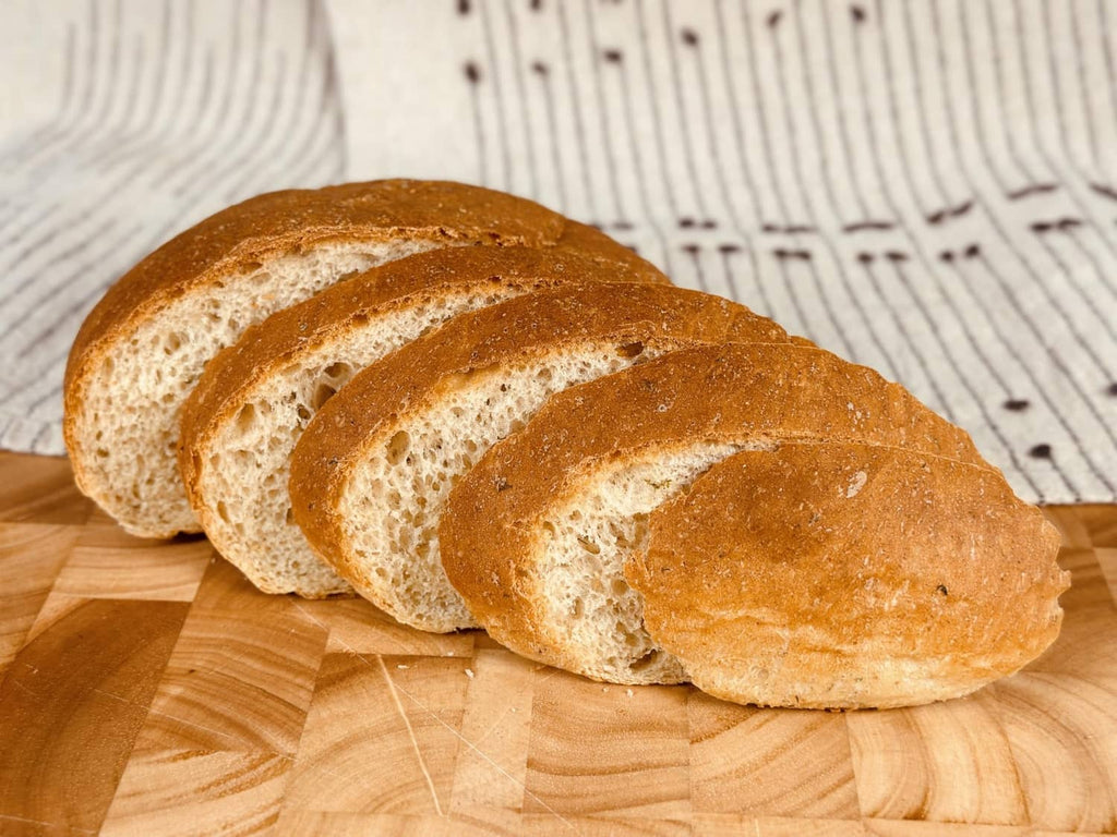Sliced golden potato bread loaf on a wood board