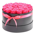 Round preserved rose bouquet in black box with pink ribbon, bright pink roses on top