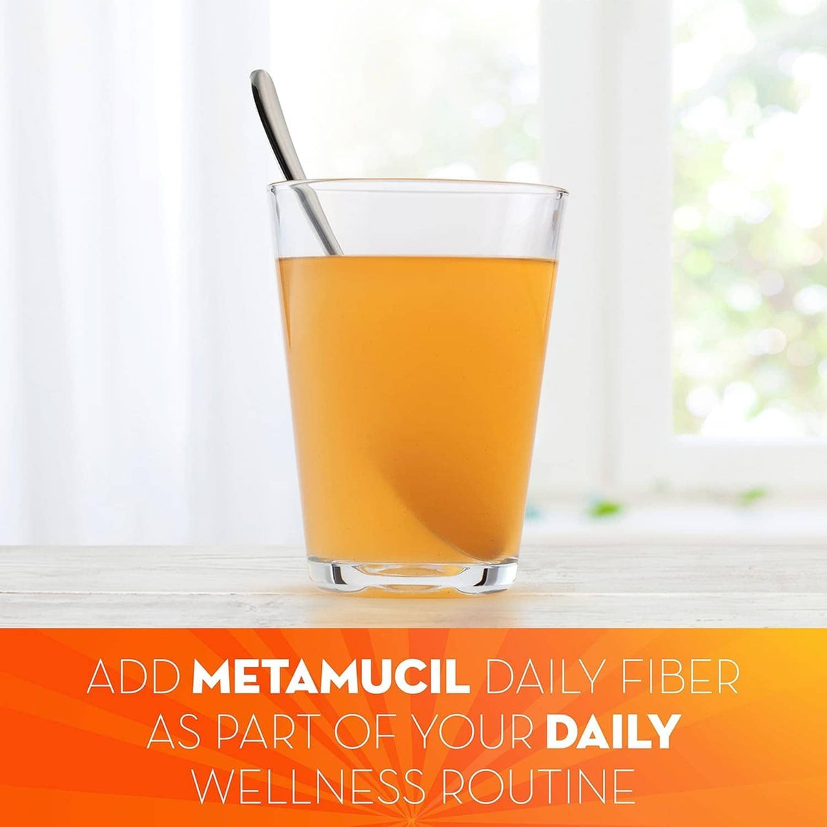 Metamucil orange fiber drink in a clear glass with spoon on a table