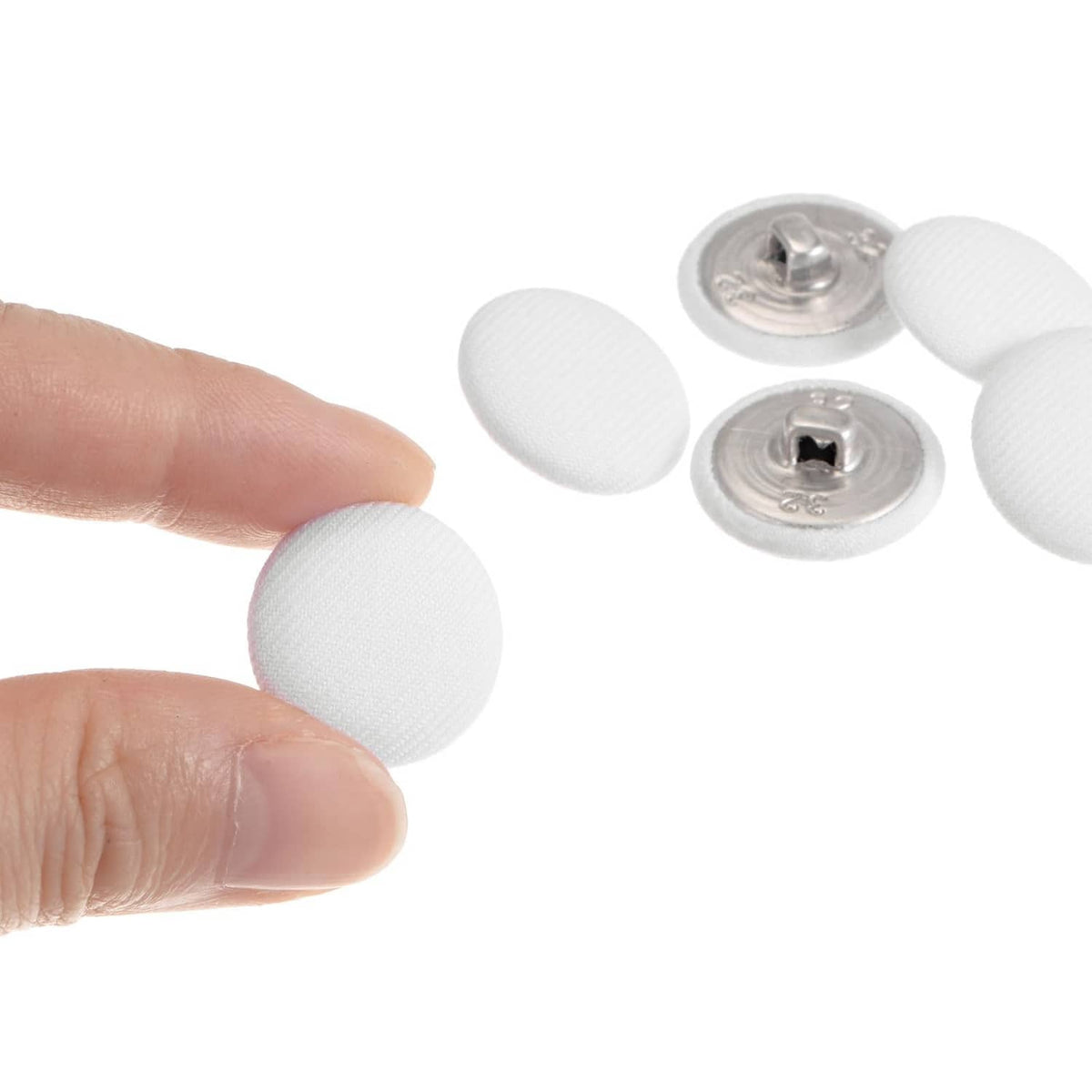 White fabric-covered round button held up, front fabric with metal shank back