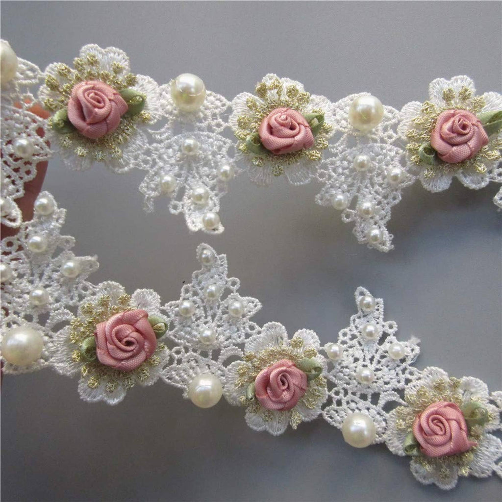 Close-up white lace trim with pink rose blooms and scattered pearl bead accents