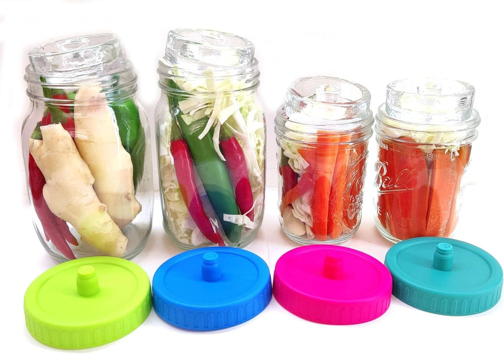 Four fermentation jars with colorful waterless airlock lids: green, blue, pink, and teal