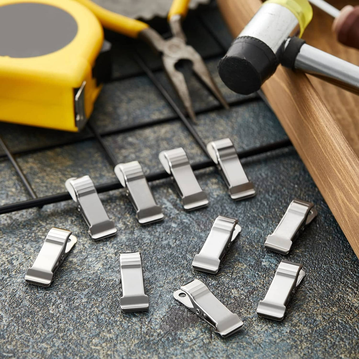 Multiple silver metal mini spring clamps laid out on a work surface