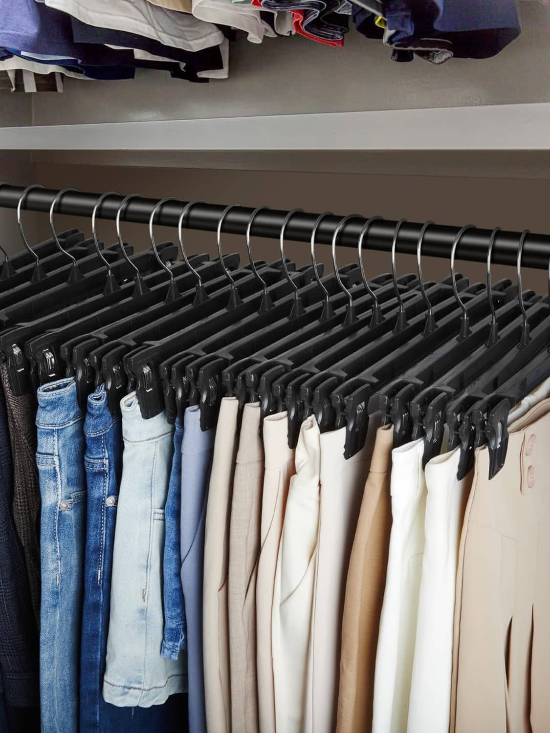 Closet rack filled with black clip pant hangers holding folded and hanging clothes