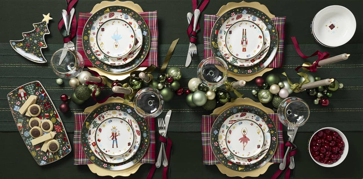 Porcelain dinnerware set on table with plates featuring dark festive borders and center nutcracker art