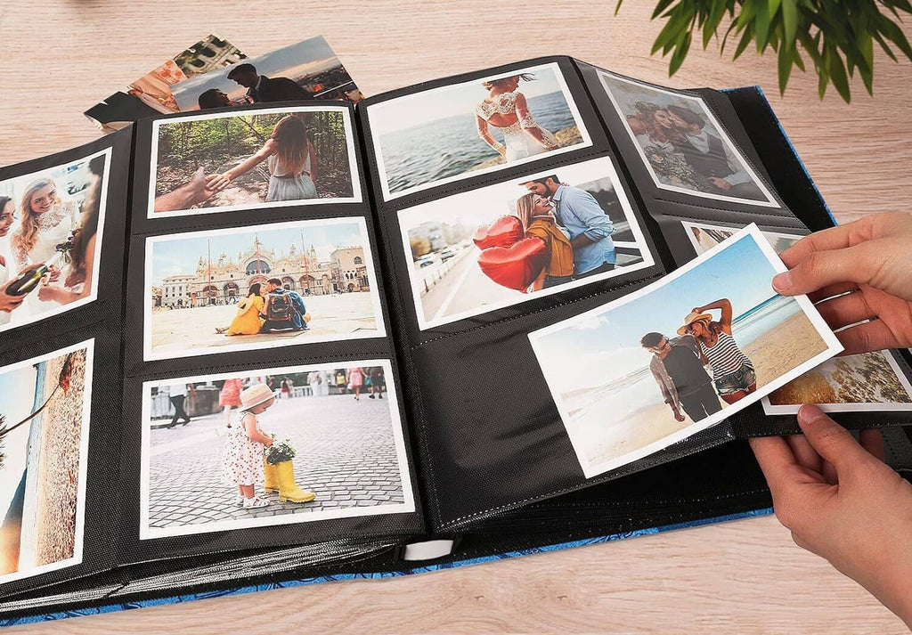 Open blue photo album with multiple photos being placed by hand.