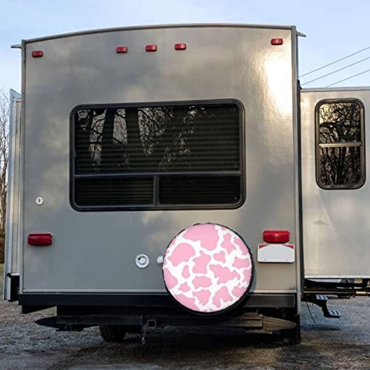 Pink cow-print spare tire cover on a rear trailer door, round cover with black edge