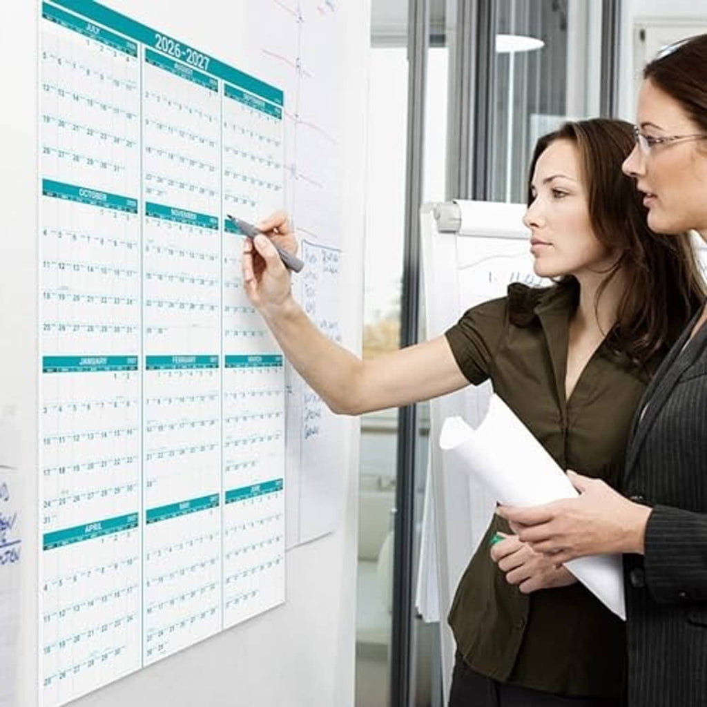 2026-2027 wall calendar mounted on a glass surface by a person