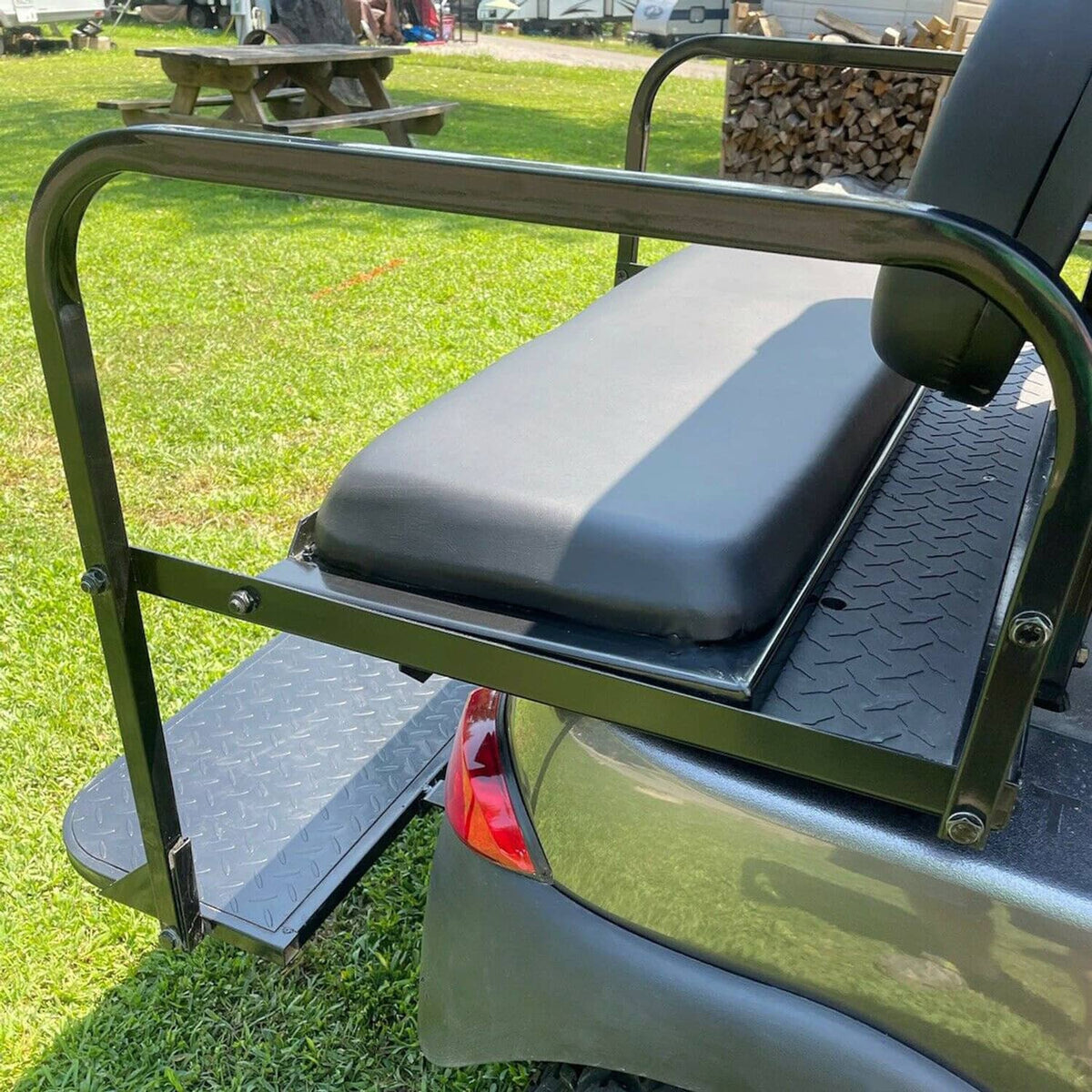 Installed black rear flip seat with padded backrest and textured platform step