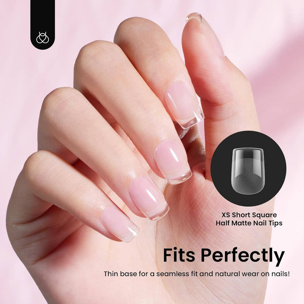 Hands wearing short square nail tips with sheer pink base and glossy nude finish