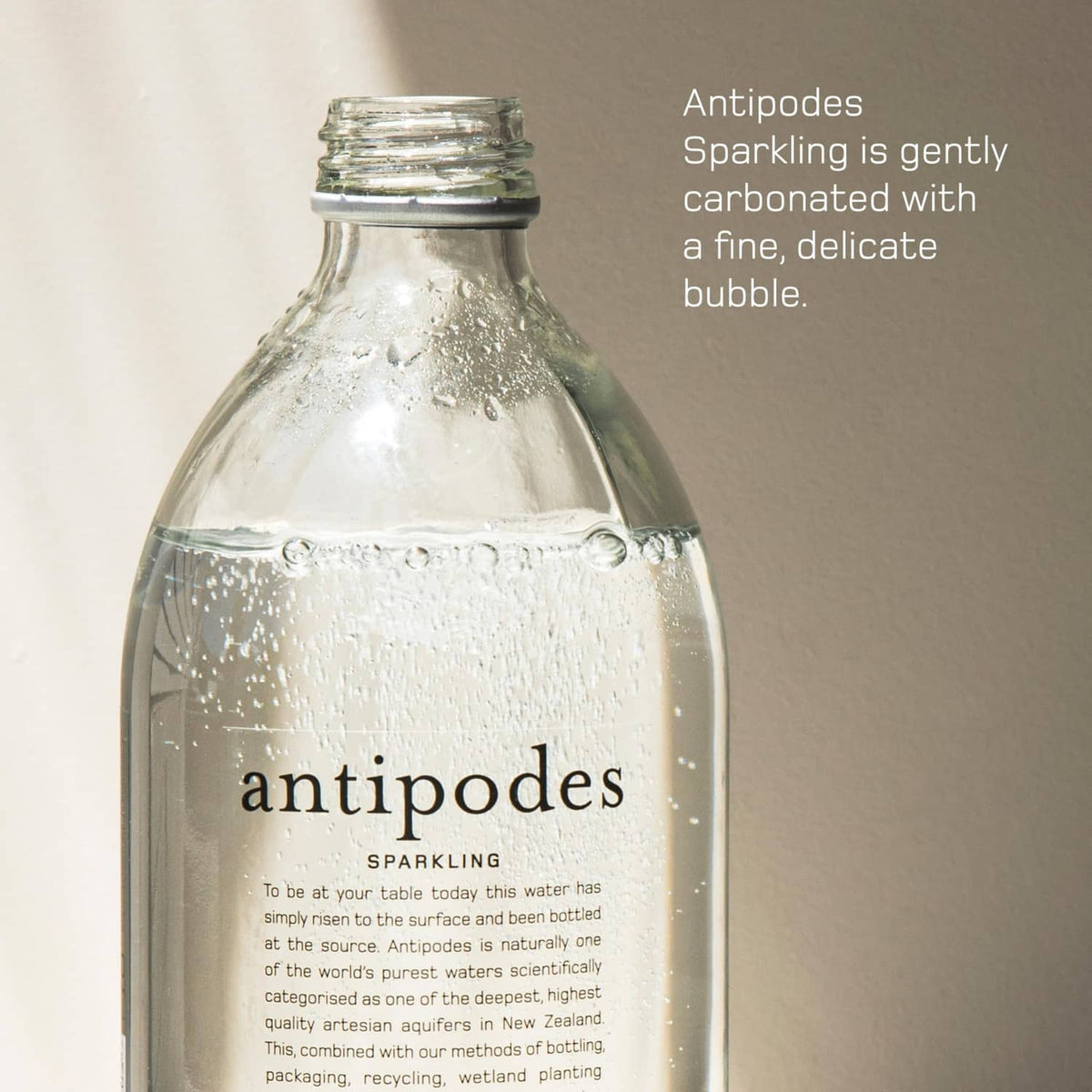Antipodes sparkling water bottle close-up, clear glass with metal cap