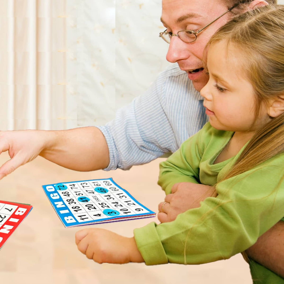 Family playing Bingo, holding a blue numbered card with FREE square.