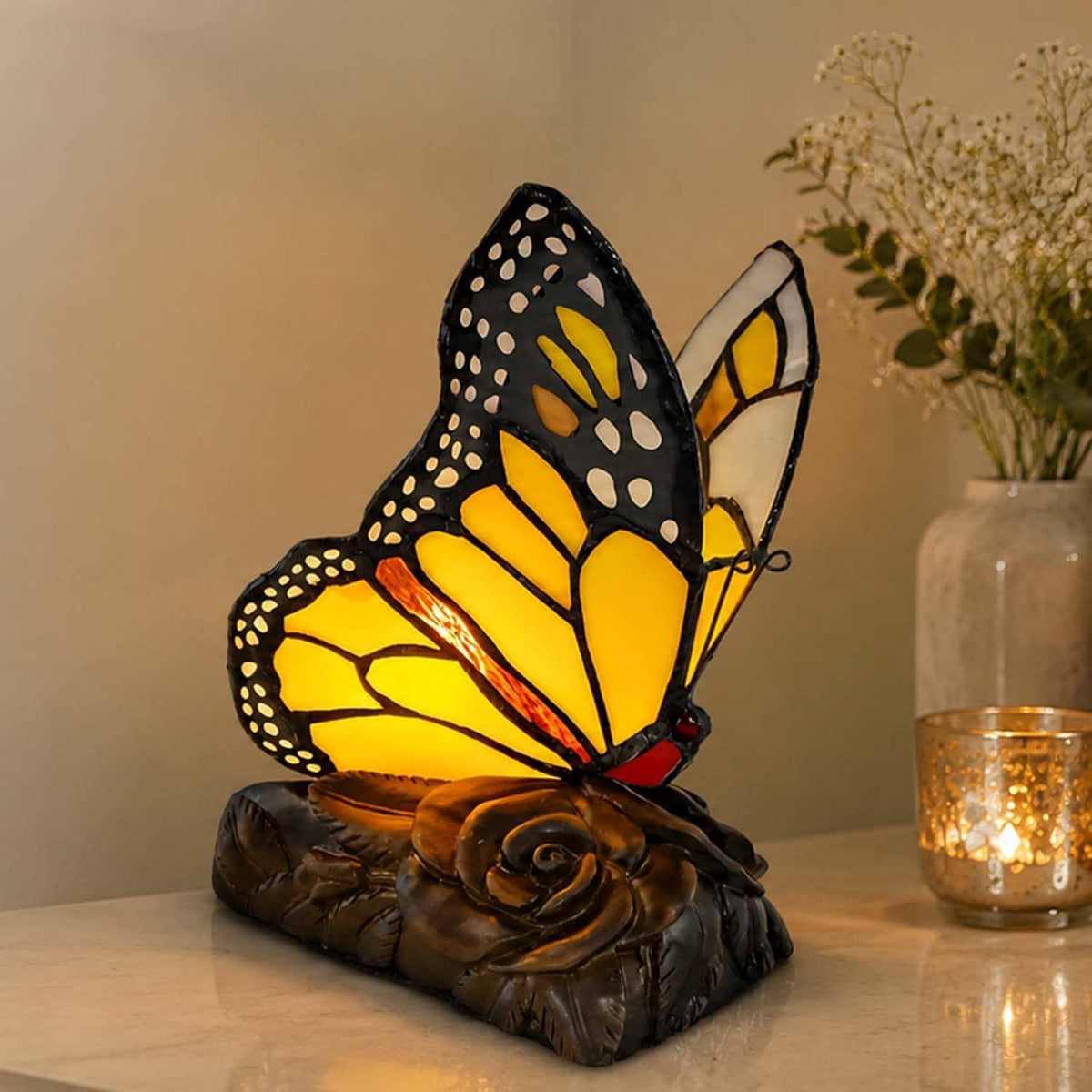 Monarch butterfly accent table lamp on tabletop with warm glow from stained-glass wings