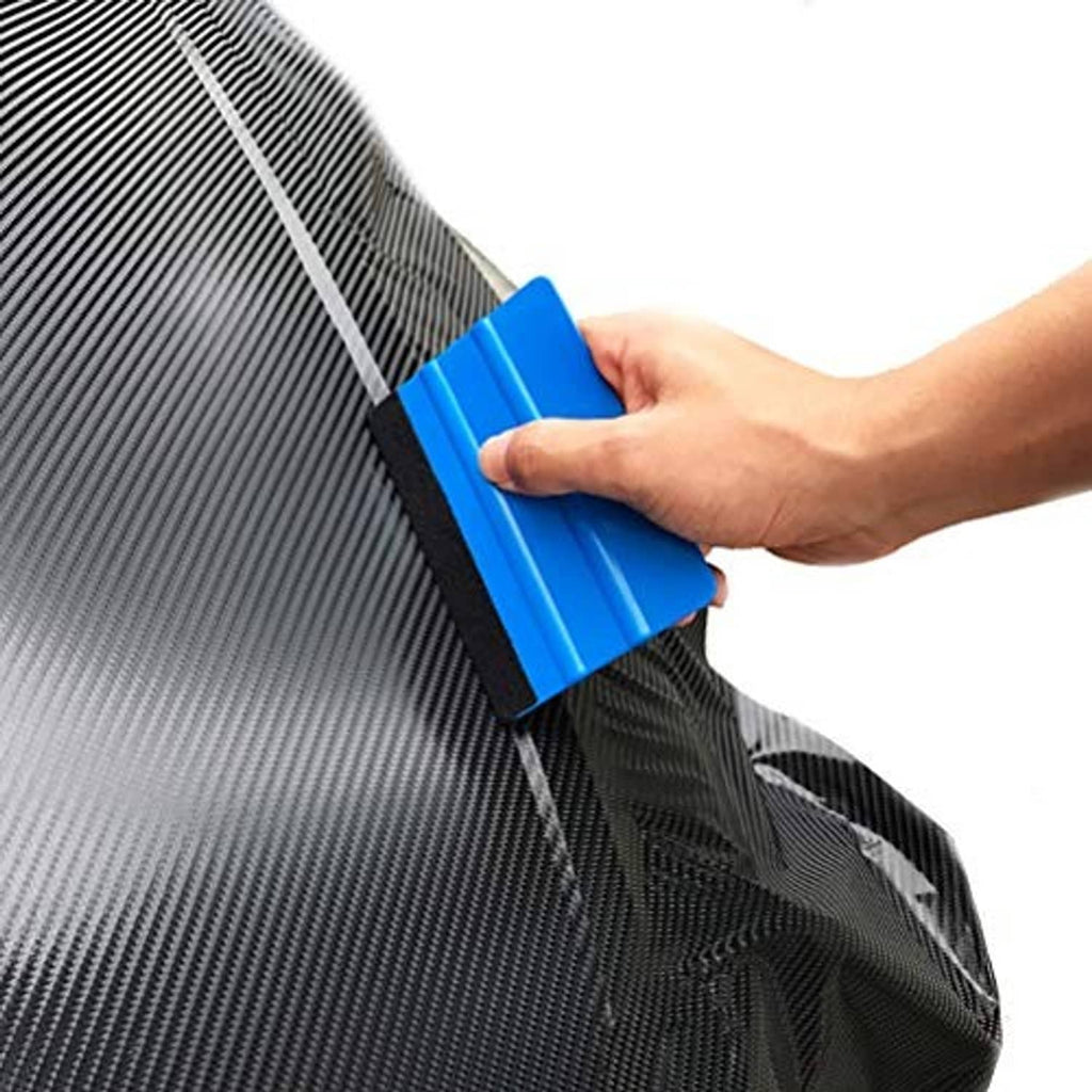 Hand using a blue vinyl edge squeegee with black felt pad on a textured surface
