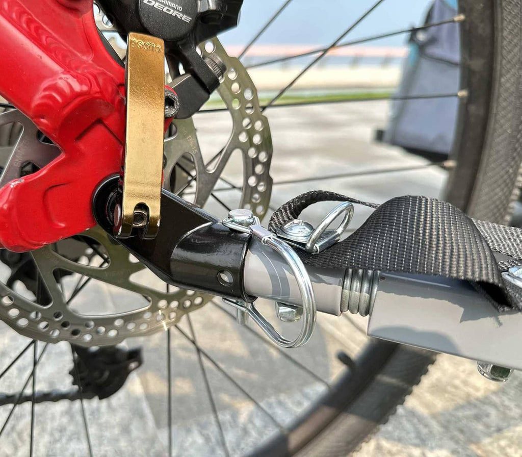 Bike trailer hitch coupler attached to bike frame with metal latch and strap