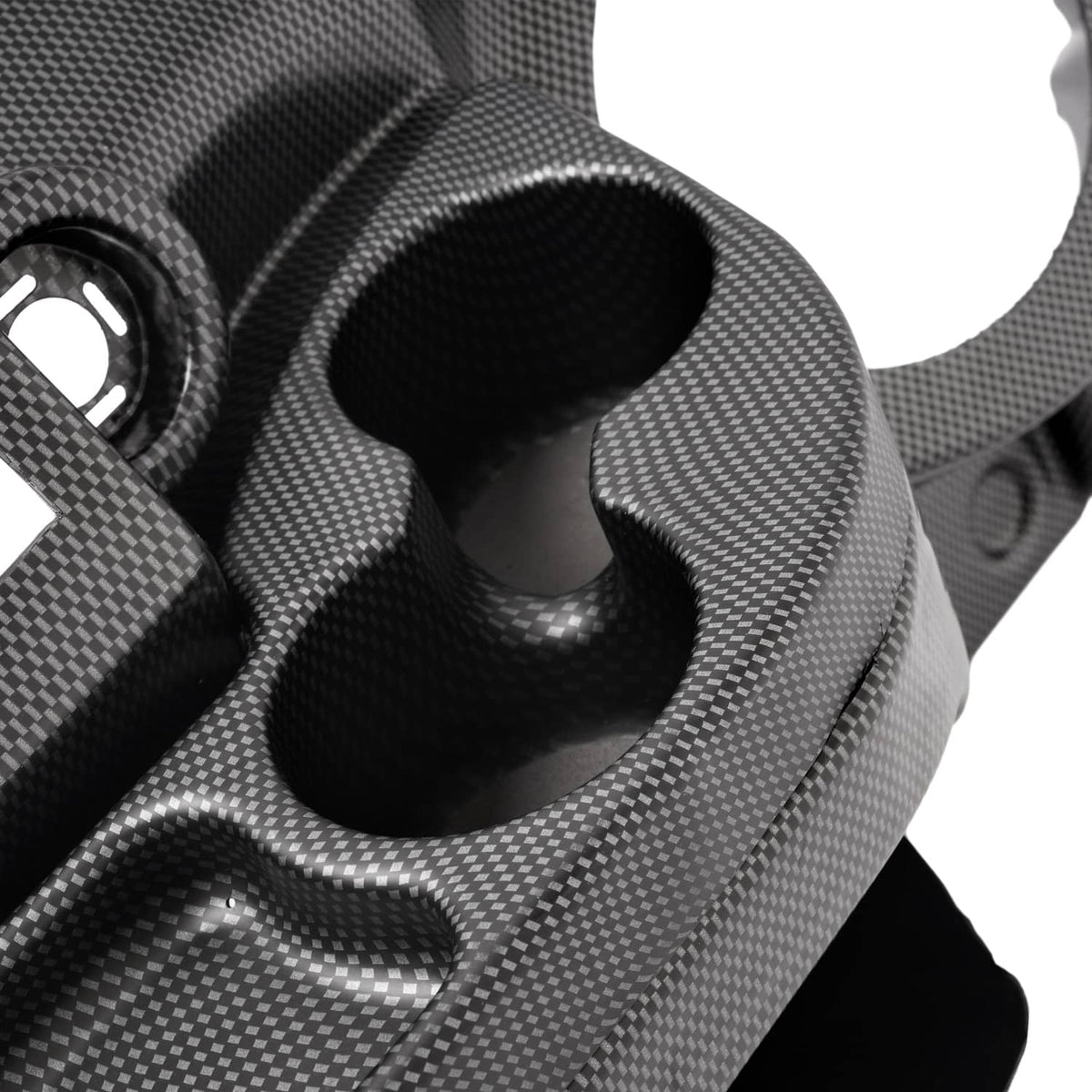 Close-up of carbon-fiber dash cover showing a curved cup-shaped cutout and textured weave.