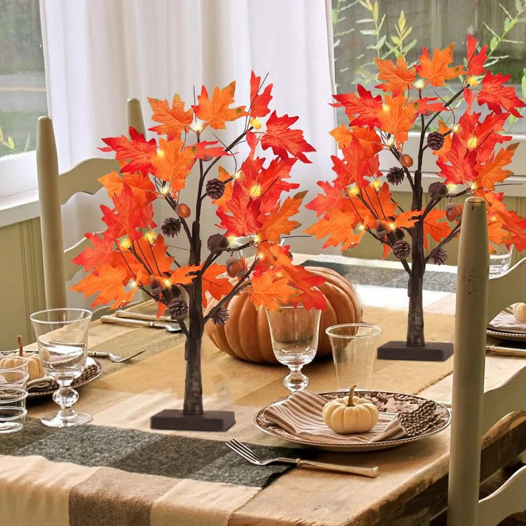 Two lighted maple leaf tree decor pieces on a dining table