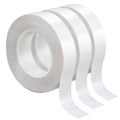Double-sided craft tape rolls stacked, with white adhesive strip flowing off the edge