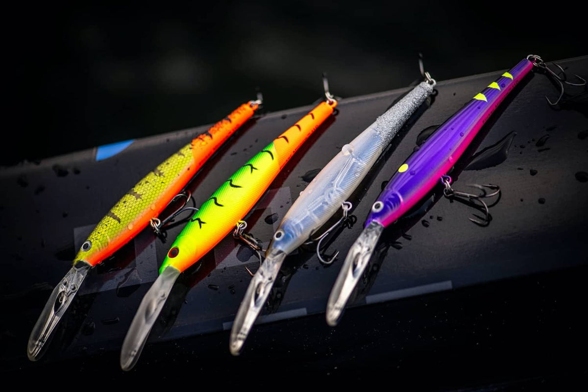 Group of colorful crankbait lures lined up: purple, orange, yellow, and white