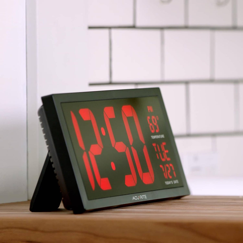 Acurite digital clock with red LED numbers on green screen, tilted on tabletop