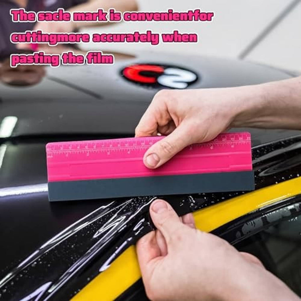 Pink vinyl squeegee with dark felt blade, held by hand for film smoothing
