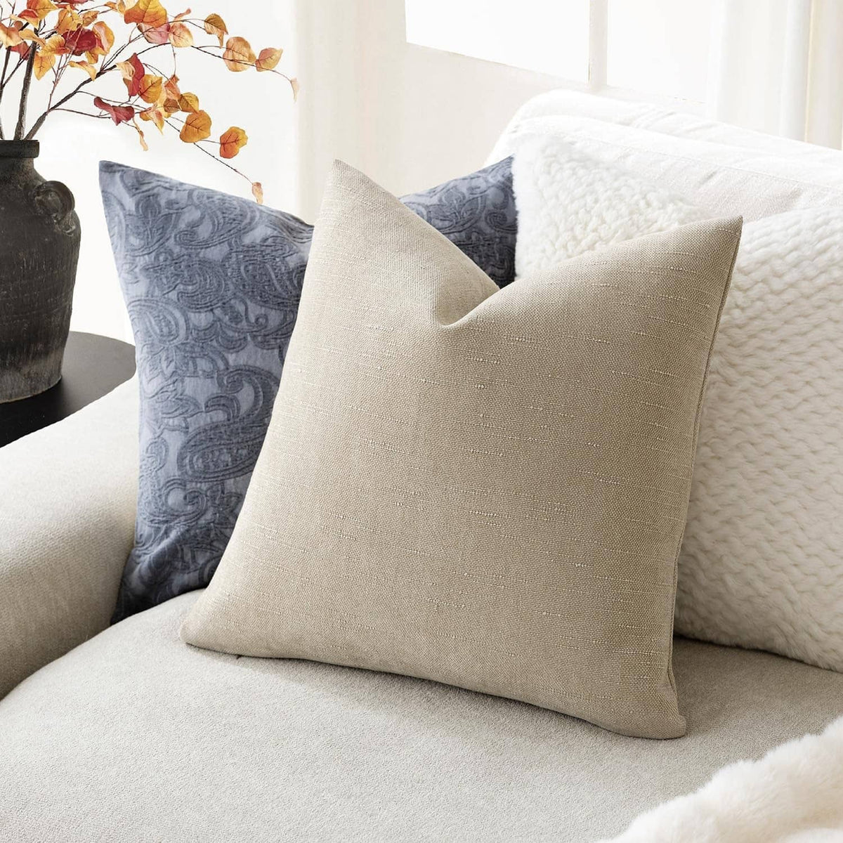 Cement chenille throw pillow, light beige square cushion with neat corners and soft texture.