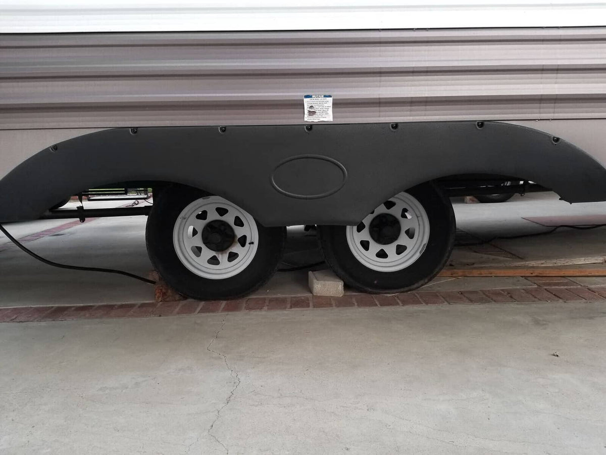 Black trailer fender skirt installed over wheel wells, curved molded cover with oval center