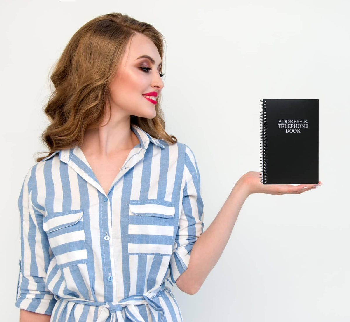 Black address & telephone book held in hand with cover title label