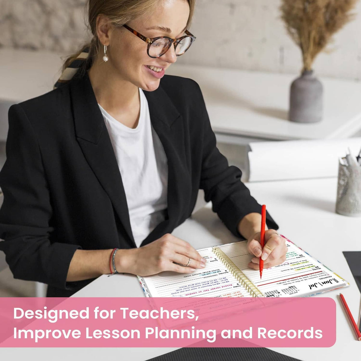 Academic planner open to schedule pages as a teacher writes with a pen