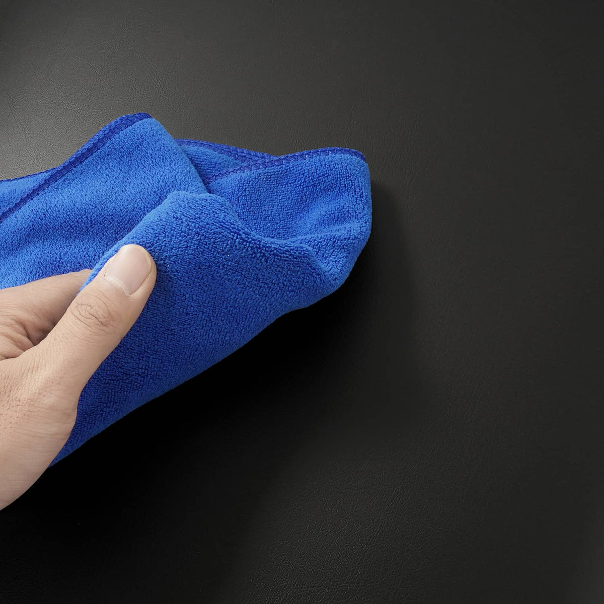 Close-up of black cushion surface being wiped with a blue cloth