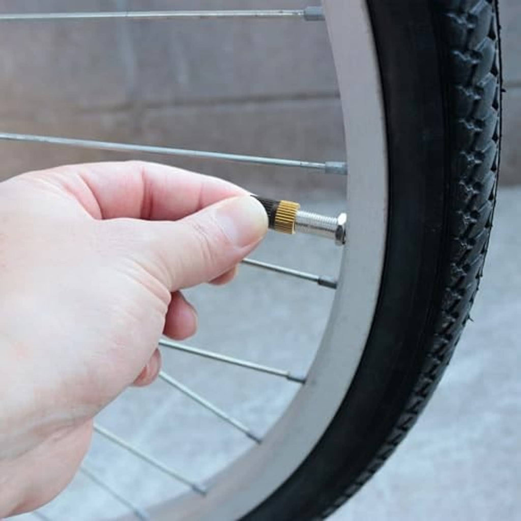 Brass Presta-to-Schrader valve adapter fitted on a bicycle wheel valve stem