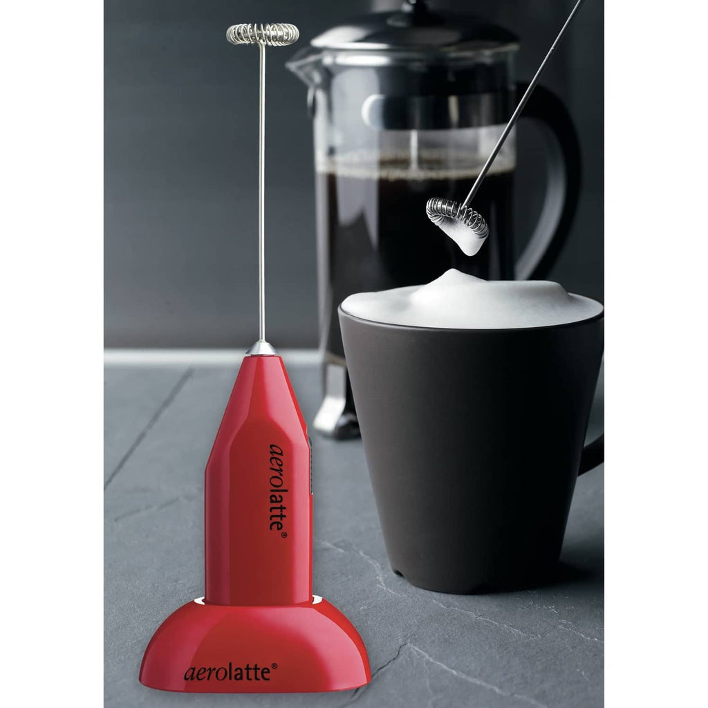 Red milk frother on counter stand next to frothing container