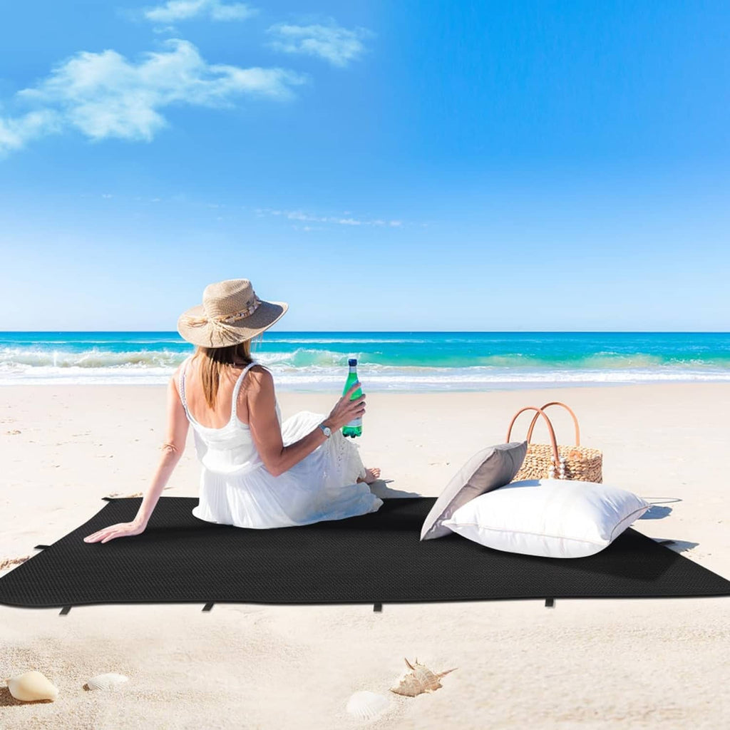 Black waterproof tarp cover laid flat on sand with tie straps visible