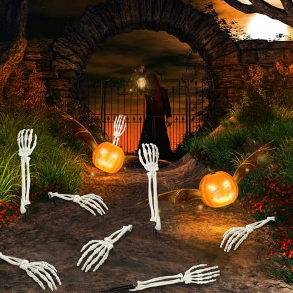 White skeleton hand stakes and arm pieces displayed along a pathway at night