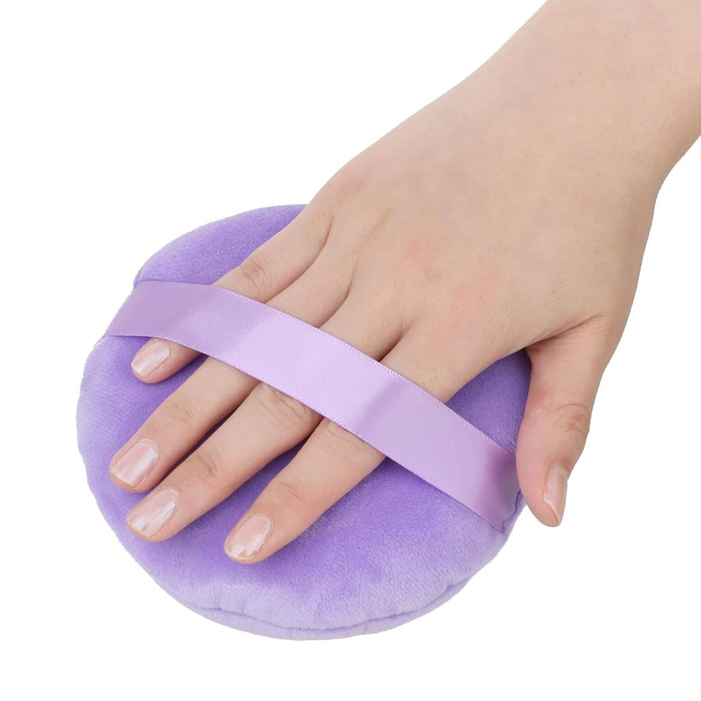 Lavender round velour makeup puff with light-lavender center strap, held in fingers
