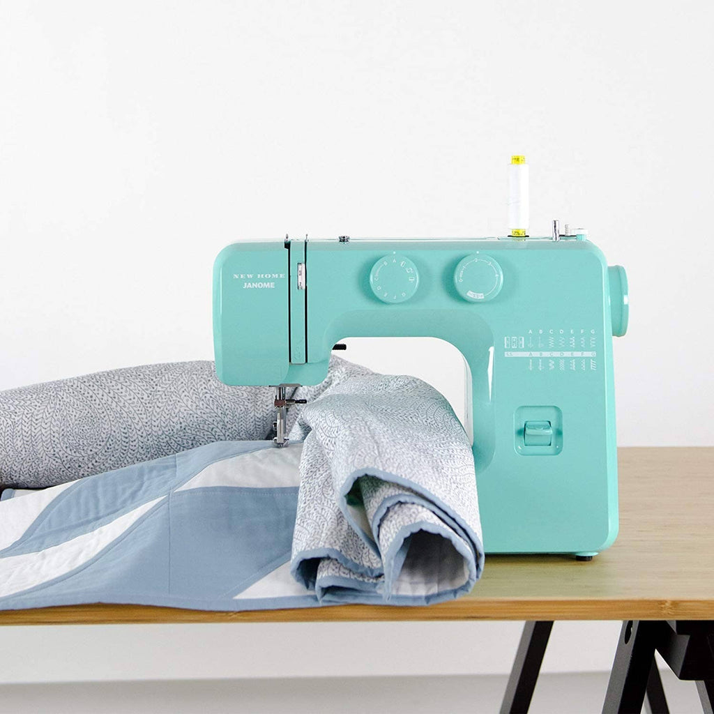 Turquoise sewing machine stitching on light gray fabric on a tabletop