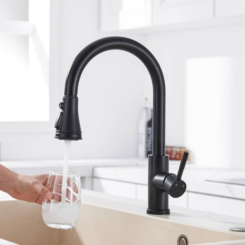 Matte black kitchen faucet with pull-down spout filling a glass with water
