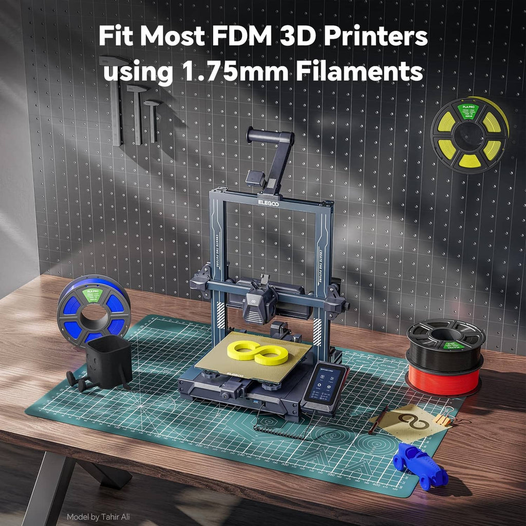Red 1.75 mm PLA filament spool next to an FDM 3D printer on a workbench