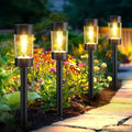 Set of eight black solar pathway lights with warm white glow, standing on ground