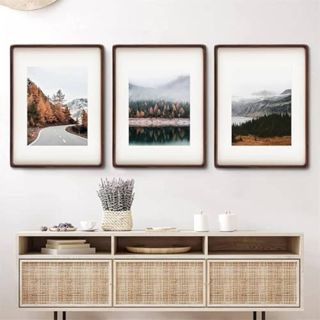 Three walnut photo frames grouped together, each with a white mat and landscape print